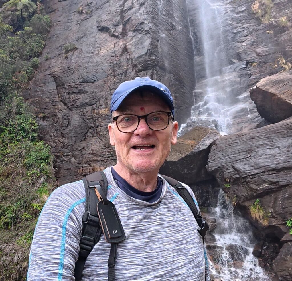 Jez at the base of Lover's Leap waterfall near Pedro's Tea Factory, Nuwara Eliya water cascading down a tall rock face.